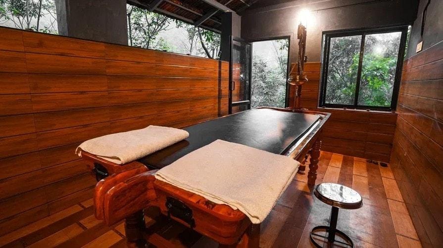 Ayurvedic treatment room with wooden massage tables at Holistic Stay Eco Resort