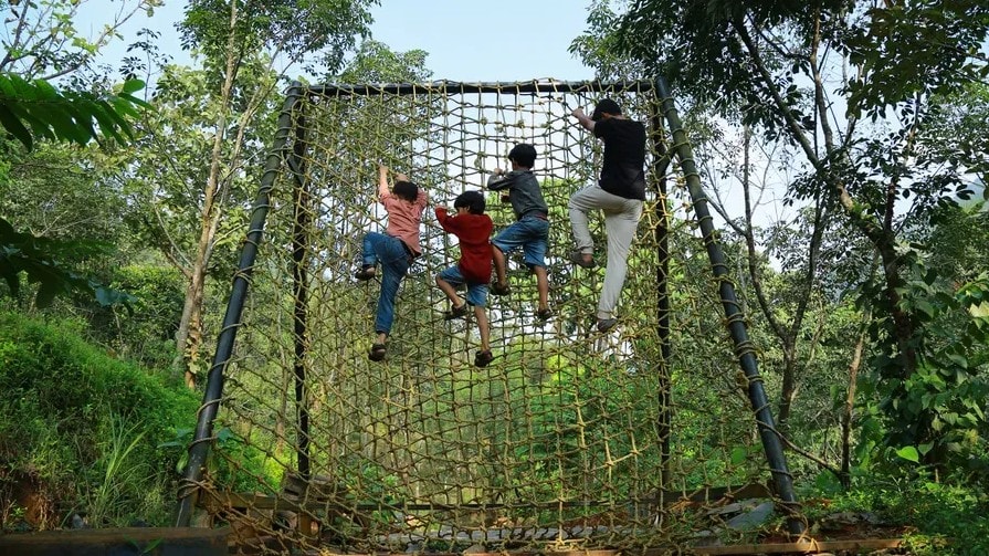 Children climbing the rope net structure outdoors at Holistic Eco-Resort