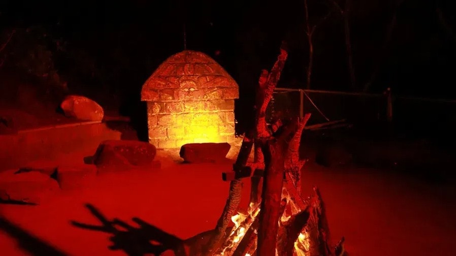 Bonfire glowing red and gold beside a stone shrine at Holistic Eco-Resort at night