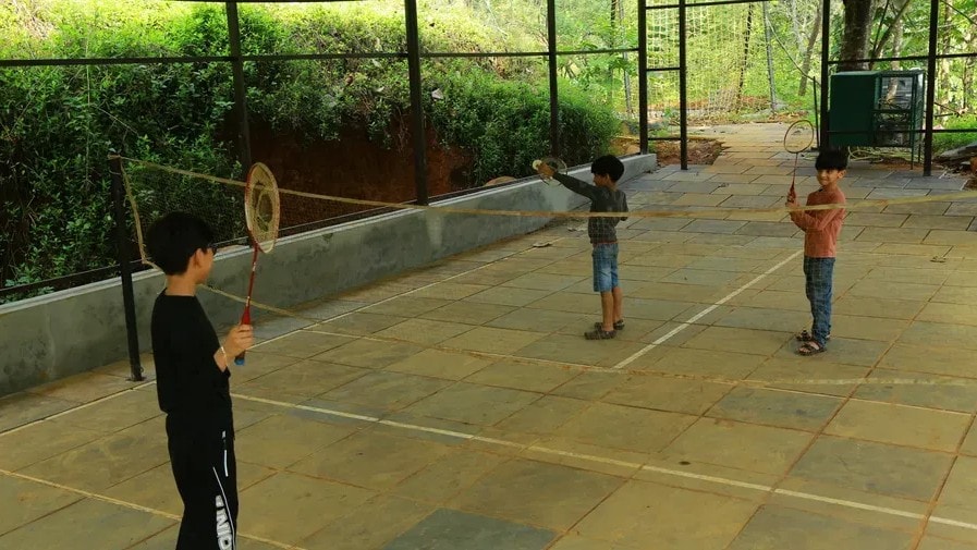 Children playing badminton on the outdoor court at Holistic Eco-Resort