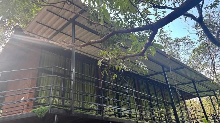 Two-storey forest-view room building with metal railings and green curtains at Holistic Eco-Resort