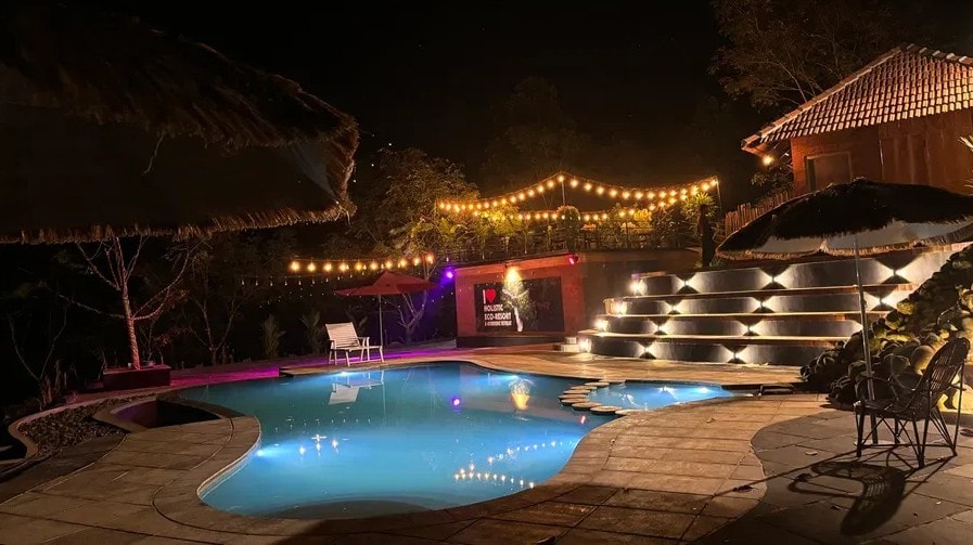 Illuminated pool at night with fairy lights and the Holistic Eco-Resort sign in the background