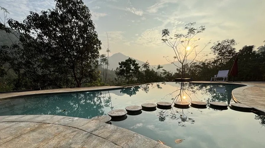 Serene pool at sunrise reflecting the mountains and trees at Holistic Eco-Resort
