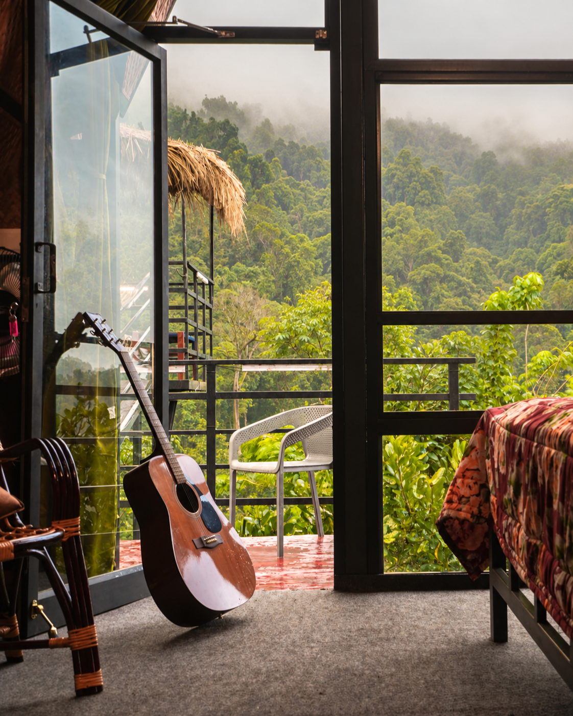 A-frame cabin nestled in dense jungle foliage with dinosaur-painted van below at Holistic Eco-Resort