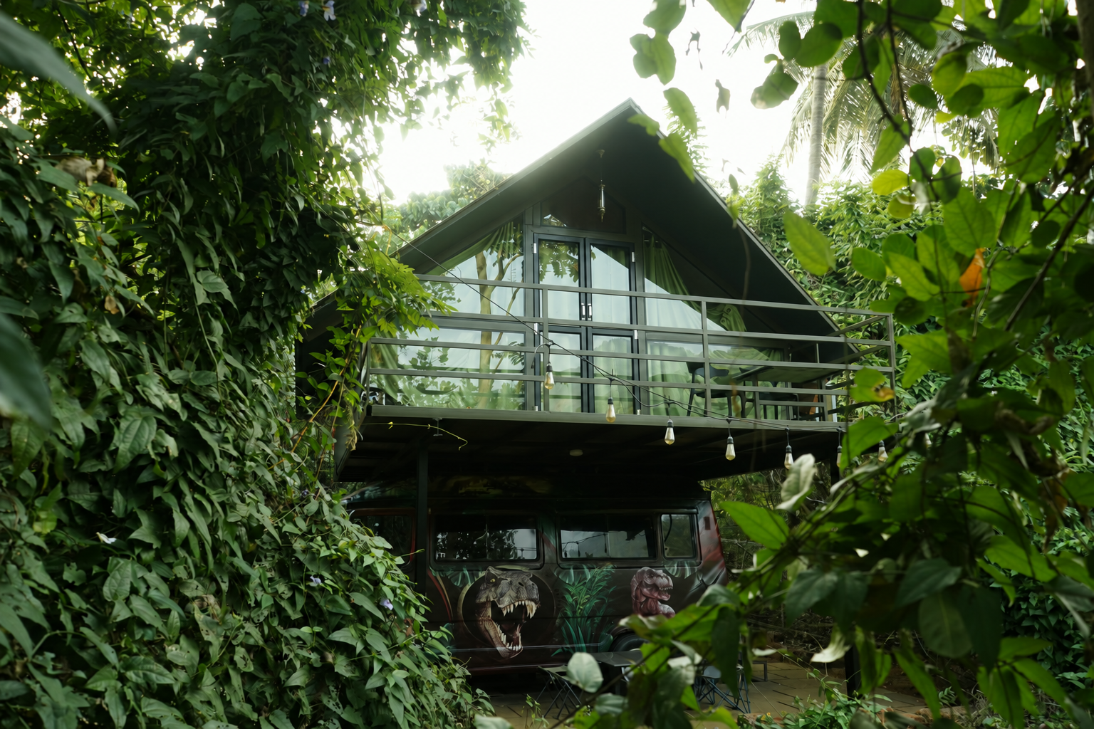 Two A-frame cabins facing each other with green walkway and mountain backdrop at Holistic Eco-Resort
