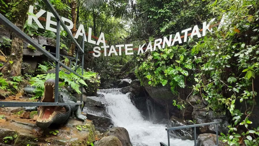 Kerala–Karnataka border waterfall with crocodile sculpture